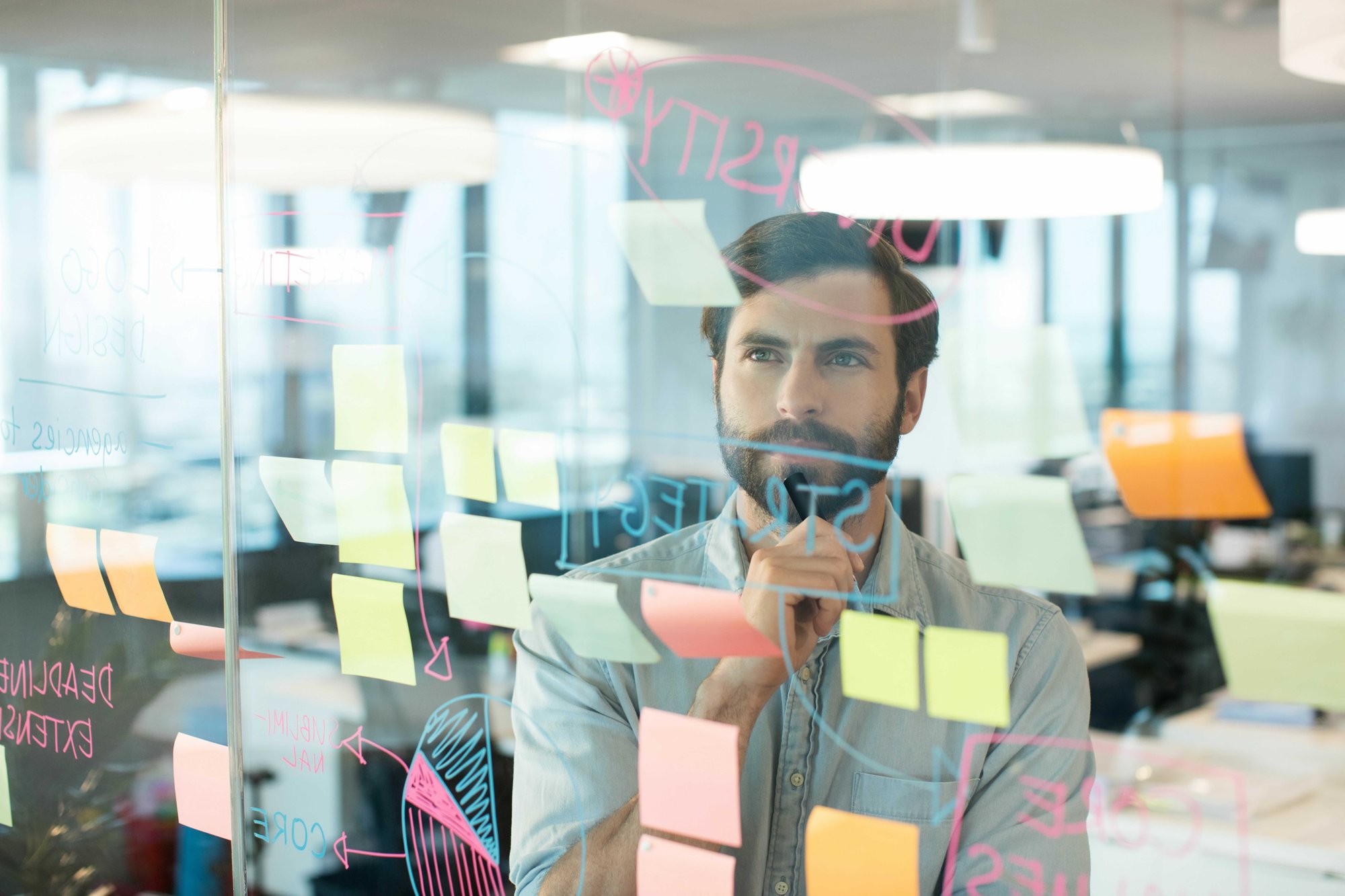 pikwizard-thoughtful-businessman-looking-at-strategy-written-on-glass_optimized